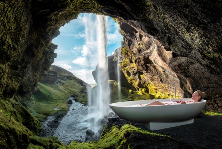 Frau in Badewanne vor einem Wasserfall